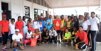 Country Manager of Massy, Deo Persaud and other employees take a photo opportunity with the top performers following the seventh annual 10km road race yesterday. (Orlando Charles photo) 