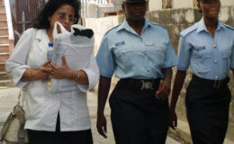 Founder of ‘Northshore Medical College’ Nailni Budhram (left) being escorted by police officers from the College’s office. 