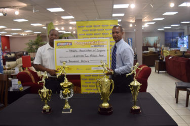 President of the AAG, Aubrey Hutson (right) receiving the sponsorship cheque yesterday from Courts (Unicomer Guyana Inc.) Marketing Managing Manager, Pernell Cummings. 