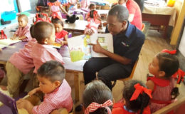 A Digicel employee reading to a group of students from the St. Cuthbert’s Mission Nursery School as part of a World Literacy Day activity on Thursday. (Digicel Guyana photo)