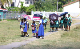 Students of the Company Road Primary School (in blue in foreground) and the Buxton Primary School (in green in background) head home after the end of classes at the Company Road Primary where both schools are now being housed. 