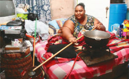 Marissa Nelson, who suffers from lymphoedema, uses a stick to turn on her gas tank as she prepares to cook at her bed side. 
