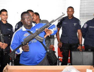 Police Sgt Matthew Haywood displays an assault rifle at the Maloney Police Station last week, one of eight firearms seized during a police exercise earlier this month. Looking on are the officers who took part in the exercise.  