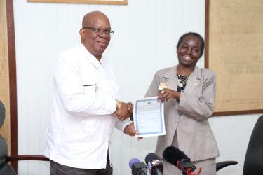 Minister of Finance Winston Jordan hands over one of 20 signed debenture certificates to General Manager of the National Insurance Scheme Doreen Nelson. (Photo by Keno George)