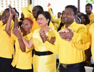 Opposition Leader Kamla Persad-Bissessar (second from right) holds hands with UNC Local Government candidates on Saturday at Couva South multipurpose hall during a song at the candidates’ presentation.  