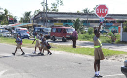 Road safety: St Pius Primary School’s Road Safety Patrol pupils helping peers cross the street after school yesterday afternoon. (Photo by Keno George)