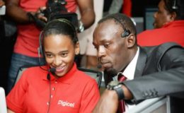  Usain Bolt (right) and Alexia Terrelonge responding to a caller inside the call centre at Digicel during his first day at work at Digicel head office yesterday