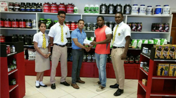 CEO of Fitness Express, Jamie McDonald handing over the donation to PE Teacher, Jaryl Moore in the presence of some students. 