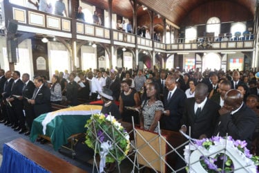 Justice Winston Moore’s widow, Vera Moore, glances over at the casket bearing her late husband’s remains during his funeral service at St Andrew’s Kirk yesterday. Standing next to her are three of her children. Also in picture (from second left) are Attorney-General Basil Williams, Speaker of the National Assembly Dr. Scotland Barton and acting President Moses Nagamootoo. (Keno George photo).
