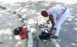 Linda, the mother of the suspect, displaying his football gear and accolades in a bid to prove his innocence in front of the Brickdam Police Station.
