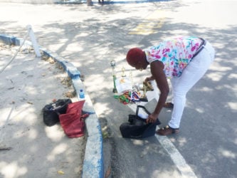 Linda, the mother of the suspect, displaying his football gear and accolades in a bid to prove his innocence in front of the Brickdam Police Station.
