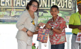 First Lady Sandra Granger making a presentation to Roland Chesney, a student, who performed outstandingly at the National Grade Six Assessment. (Ministry of the Presidency photo)