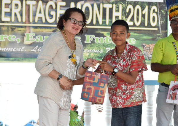 First Lady Sandra Granger making a presentation to Roland Chesney, a student, who performed outstandingly at the National Grade Six Assessment. (Ministry of the Presidency photo)