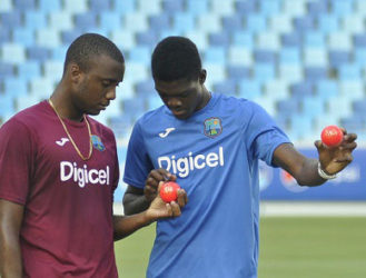 PACE TWIN: Rookie fast bowlers Miguel Cummins (left) and Alzarri Joseph examine the pink ball during practice ahead of today’s start of the opening Test in Dubai. (Photo courtesy WICB Media)  