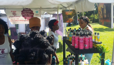 Jasmine Farley (red flowers in hair) answers the questions of a potential customer visiting her booth during the Exhibition