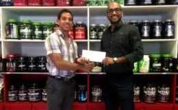 Jamie Mc Donald of Fitness Express hands over the sponsorship contribution  to Navin Singh of the Guyana Amateur Powerlifting Federation.
