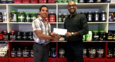 Jamie Mc Donald of Fitness Express hands over the sponsorship contribution  to Navin Singh of the Guyana Amateur Powerlifting Federation. 