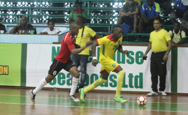 Nyk Nichols (28) of Guyana trying to launch an attack while being pursued by a Surinamese player during their matchup at the Cliff Anderson Sports Hall in the Inter-Guiana Games Futsal encounter yesterday. (Orlando Charles photo)   