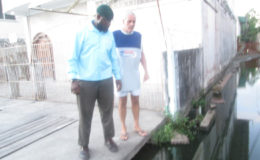 Joseph Ramsey (at right right) shows City Engineer Rasheed Kellman the water which inundates his entrance. 
