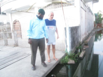 Joseph Ramsey (at right right) shows City Engineer Rasheed Kellman the water which inundates his entrance. 
