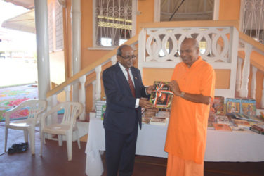 Indian High Commissioner V Mahalingam (left) hands over the books to Principal of the Hindu College Swami Aksharananda