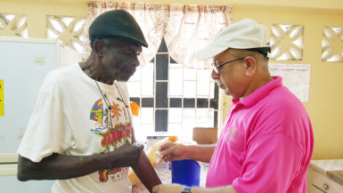 Dr. Syed Ghazi (right) taking a blood sample from 84-year-old James Daniels