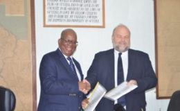 US Ambassador Perry Holloway and Finance Minister Winston Jordan shake hands after the signing of the agreement yesterday.
