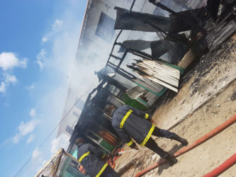 Fire fighters on the scene of yesterday’s fire which completely destroyed three stalls in the Bartica commercial zone