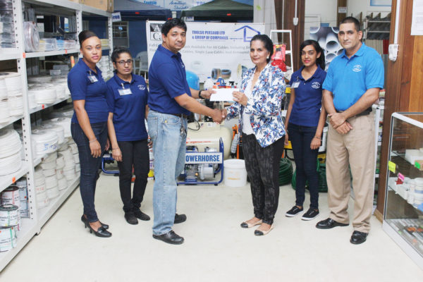 General Manager of Toolsie Persaud Ltd Ray Sukhnandan hands over a cheque to Deborah Ramotar-Skeete, the Administrative Coordinator of the Guyana Book Foundation to aid in its literacy programmes. (Photo by Keno George)