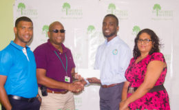 Assistant Director of Sport Brian Smith receives the sponsorship package from Banks DIH Water Beverage Manager Clive Pellew while Errol Nelson and Ms. Sooklall of the NSC look on.