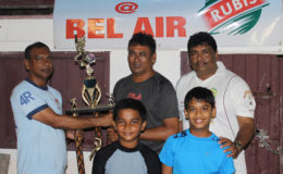At left, Ramesh Sunich of  the Trophy Stall hands over the winning trophy to Anil Persaud of the East Coast Cricket Committee in the presence of two under 15 players and Guyana Floodlight Softball Cricket Association representative Anil Beharry.
