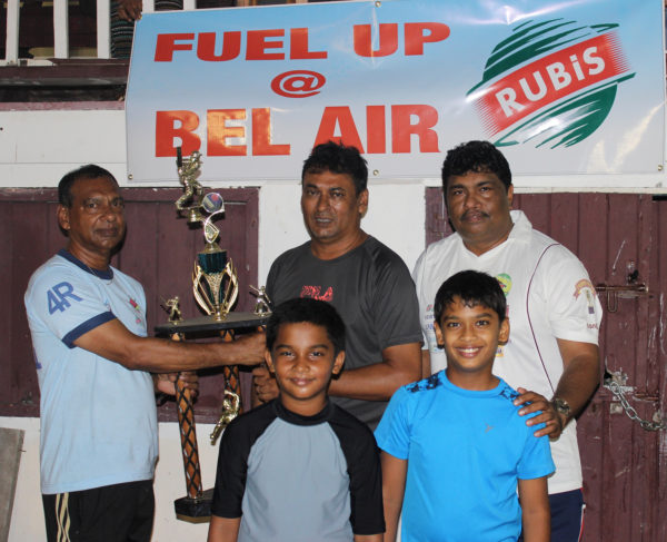 At left, Ramesh Sunich of  the Trophy Stall hands over the winning trophy to Anil Persaud of the East Coast Cricket Committee in the presence of two under 15 players and Guyana Floodlight Softball Cricket Association representative Anil Beharry.