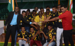 Guyana Coach Levi Nedd (center) and his victorious boys team share a photo with Director of Sports Christopher Jones (left).