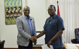 Minister of State, Joseph Harmon (left) shakes hands with the Commissioner of the newly established Board of Inquiry, Winston Cosbert. (Ministry of the Presidency photo)