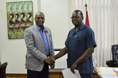 Minister of State, Joseph Harmon (left) shakes hands with the Commissioner of the newly established Board of Inquiry, Winston Cosbert. (Ministry of the Presidency photo) 