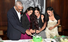 President David Granger sticks the birthday cake with (from left)  Radha Mansaram, Rajshri Mansaram and  Reenica Mansaram. (Ministry of the Presidency photo)  
 