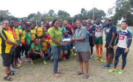 Vice President of the GOA, Noel Adonis presenting the sponsorship cheque to Secretary of the union, Petal Grant yesterday in the presence of the players and president, Peter Green (extream left). 
