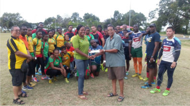 Vice President of the GOA, Noel Adonis presenting the sponsorship cheque to Secretary of the union, Petal Grant yesterday in the presence of the players and president, Peter Green (extream left).  