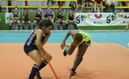 Sonia Jardine (left) Pizza Hut GCC dribbling the onrushing Hikers defender during divisional meeting in the GTT National Indoor Hockey Championship at the National Gymnasium 