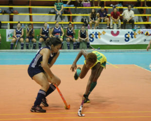 Sonia Jardine (left) Pizza Hut GCC dribbling the onrushing Hikers defender during divisional meeting in the GTT National Indoor Hockey Championship at the National Gymnasium 