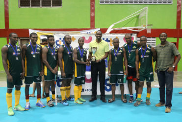 Hikers 1st Division Captain Robert France (centre) collecting the championship trophy from Director of Sports Christopher Jones after defeating Bounty GCC in the GTT National Indoor Hockey Tournament final.