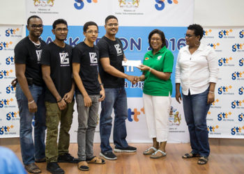 Team leader and CEO of V75 Eldon Mark receiving the first prize cheque for $300,000 from Minister of Public Telecommunications Catherine Hughes at the recently concluded Hackathon. 