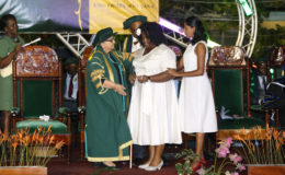 Odessa Blair (centre), aided by a colleague, is greeted by Pro Chancellor of the University of Guyana Bibi Shadick during the 50th Convocation Ceremony.