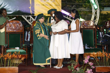 Odessa Blair (centre), aided by a colleague, is greeted by Pro Chancellor of the University of Guyana Bibi Shadick during the 50th Convocation Ceremony.