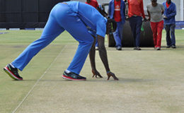 Jason Holder takes a close look at the pitch. (WICB Media Photos/Philip Spooner)