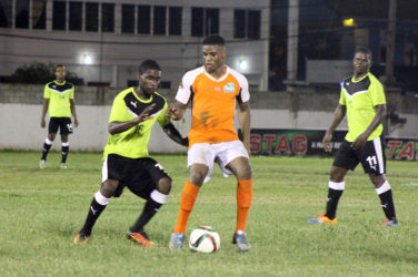 Eon Alleyne (centre) of Fruta Conquerors bracing himself for the impending challenge from a Topp XX player during their matchup in the GFF Stag Beer Elite League Season II opening night at the DCC ground