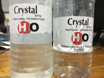 The bottle of water on the left covered with the grey strip.  At right, the hidden labelling is revealed once the strip was removed. 