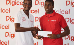 Fruta Conquerors talisman Jeremy Garrett (right) accepting the ticket from Digicel Customer Care executive Sherwin Osbourne for his training stint at European giant Sporting Lisbon of Portugal.