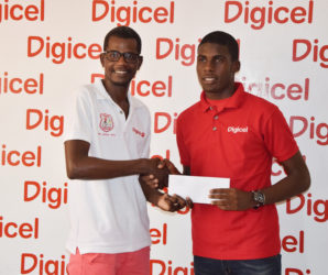 Fruta Conquerors talisman Jeremy Garrett (right) accepting the ticket from Digicel Customer Care executive Sherwin Osbourne for his training stint at European giant Sporting Lisbon of Portugal. 