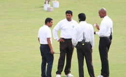 BANGING HEADS: Match officials mull over the state of play during the rain-affected contest at Queen’s Park Oval. (Photo courtesy WICB Media)